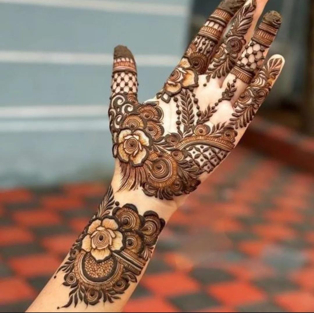 A person showing henna on their hands with a brown background