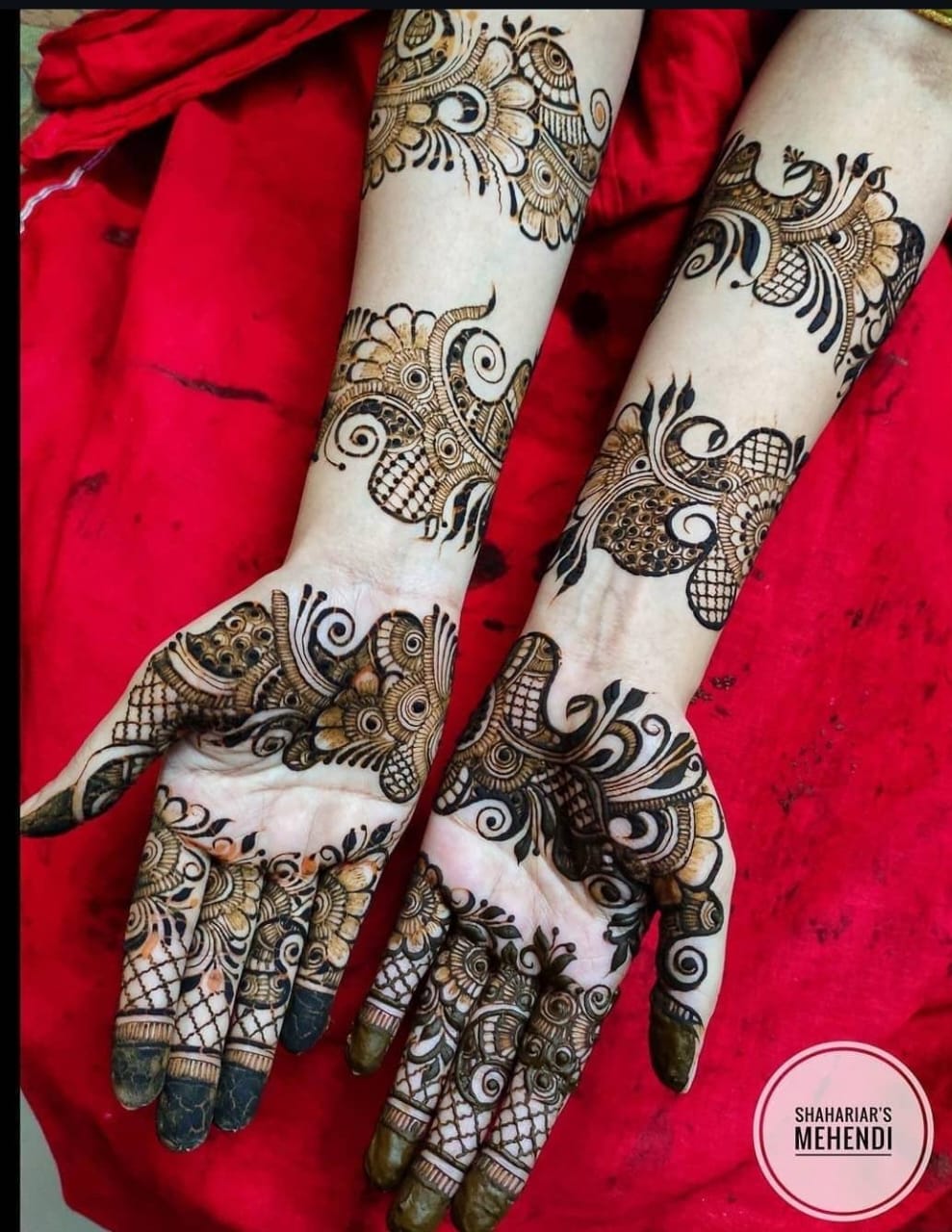 A person showing henna on their hands with a teal background