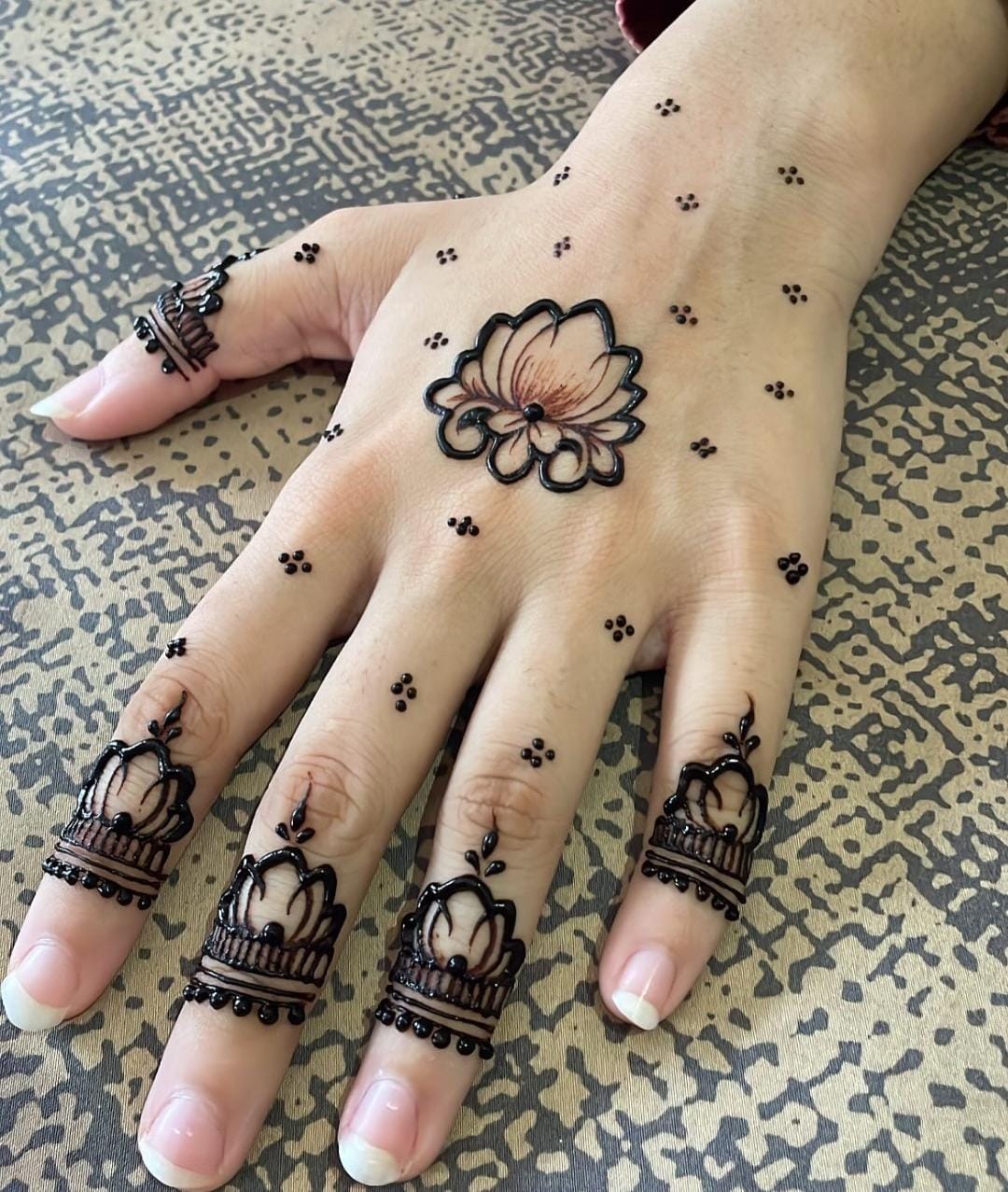 A person showing henna on their hands with a dark background
